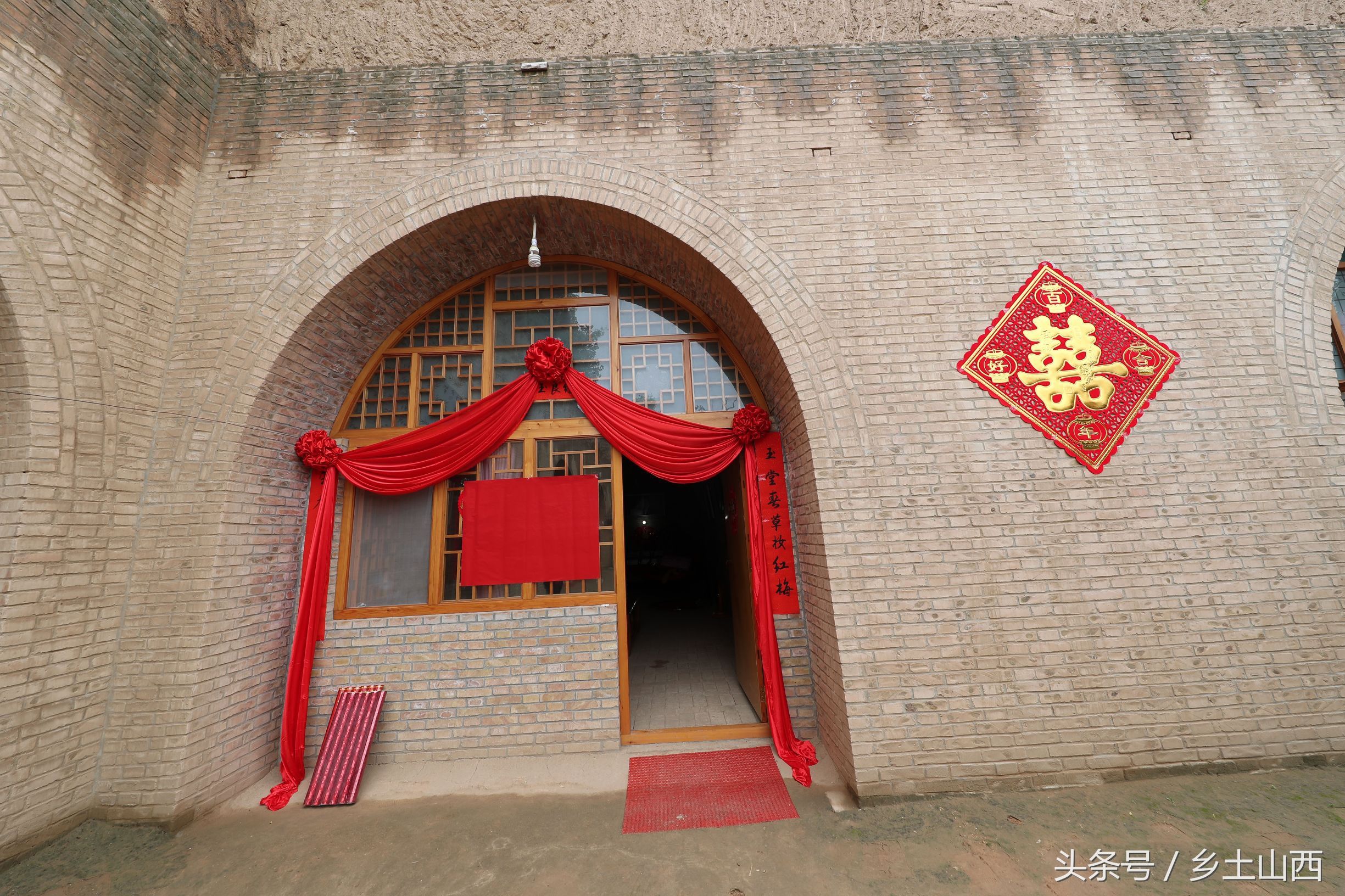 硕大的红绸和喜字装点着红砖建造的新式窑洞,窑洞前安装的实木门窗都