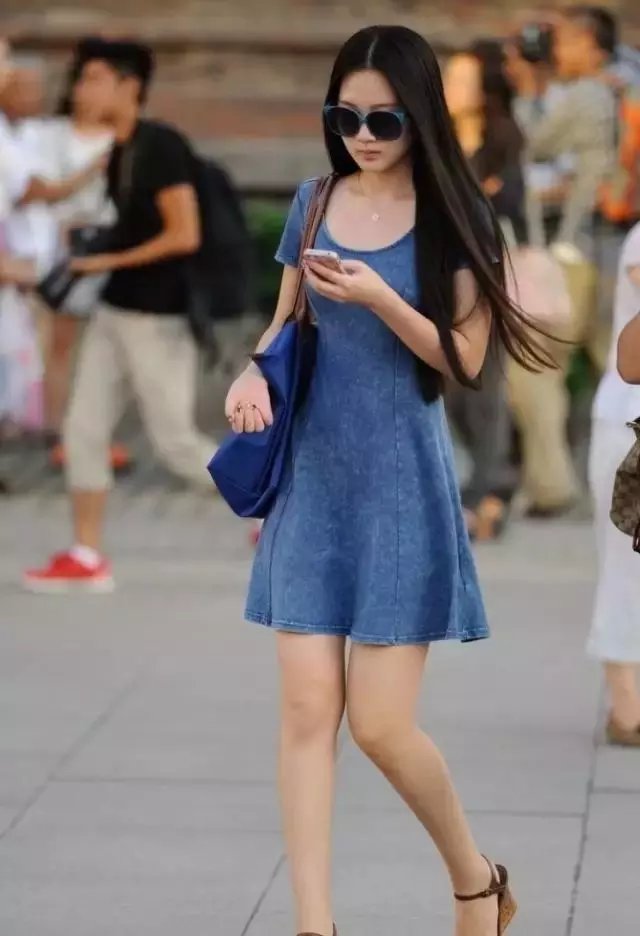 路人街拍，小姐姐穿着黑色紧身的小皮裙，露出白皙的小腿很迷人