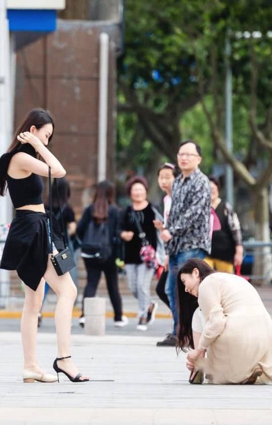 俏皮小姐姐嫌弃高跟鞋太高，与闺蜜当街换鞋，露出精美小脚丫
