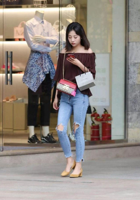  漂亮|街拍：专注看手机的小姐姐，一字肩上衣+露洞牛仔裤，时尚又漂亮