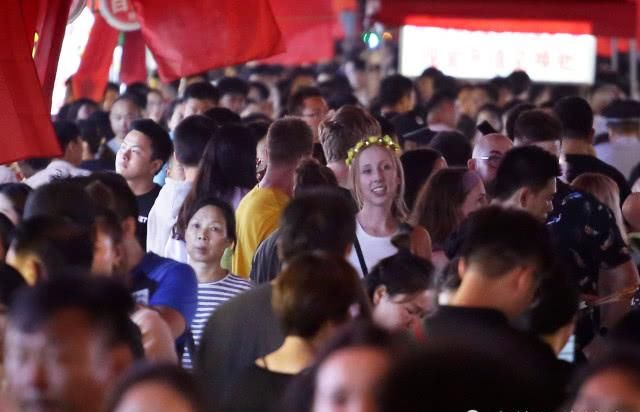 外国游客扎堆逛小吃街，小伙忙着吃串，美女专挑人多的地方留影