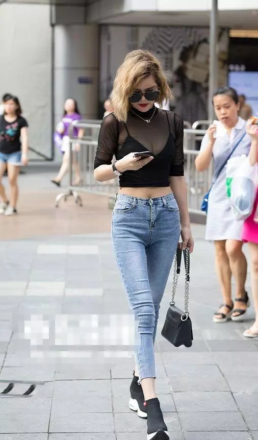 路人街拍，小姐姐身穿紧身的浅蓝色牛仔裤，勾勒出迷人的双腿