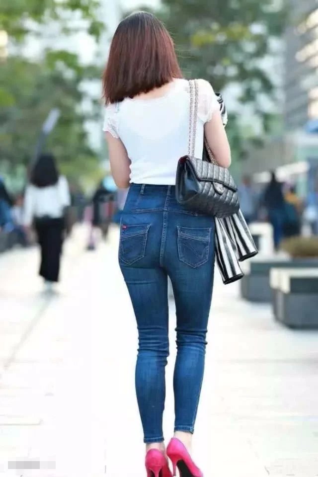 气质小姐姐白色T恤搭配牛仔裤，紧绷感十足，边走边玩手机很洋气