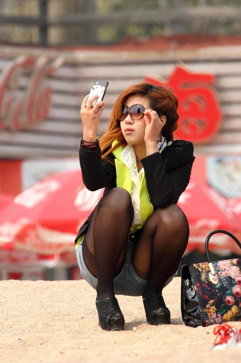 街拍:阳光沙滩上蹲姿曼妙的美女，细腻的黑丝更加灵动