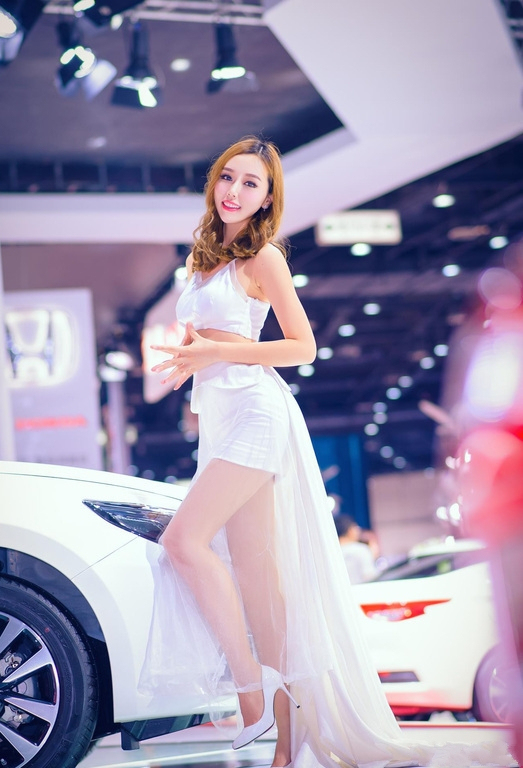 明艳娇俏的美女车模，白色纱裙自带满满仙气，笑容甜美引全场瞩目
