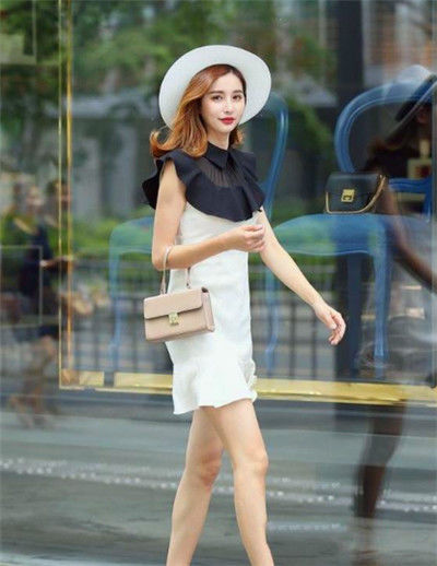  小美女：街拍：小美女身穿黑色套装，手里拿着包包，笑容甜美