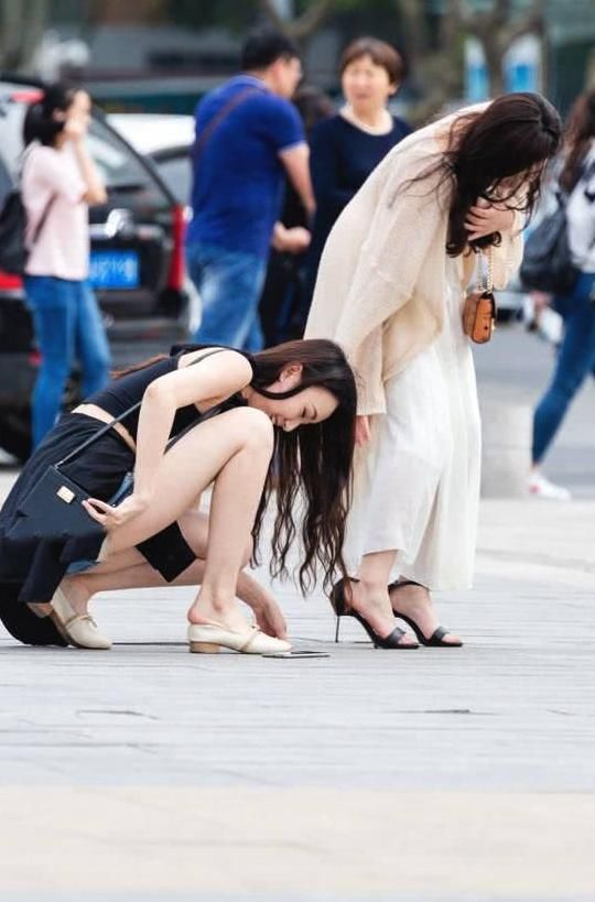 俏皮小姐姐嫌弃高跟鞋太高，与闺蜜当街换鞋，露出精美小脚丫