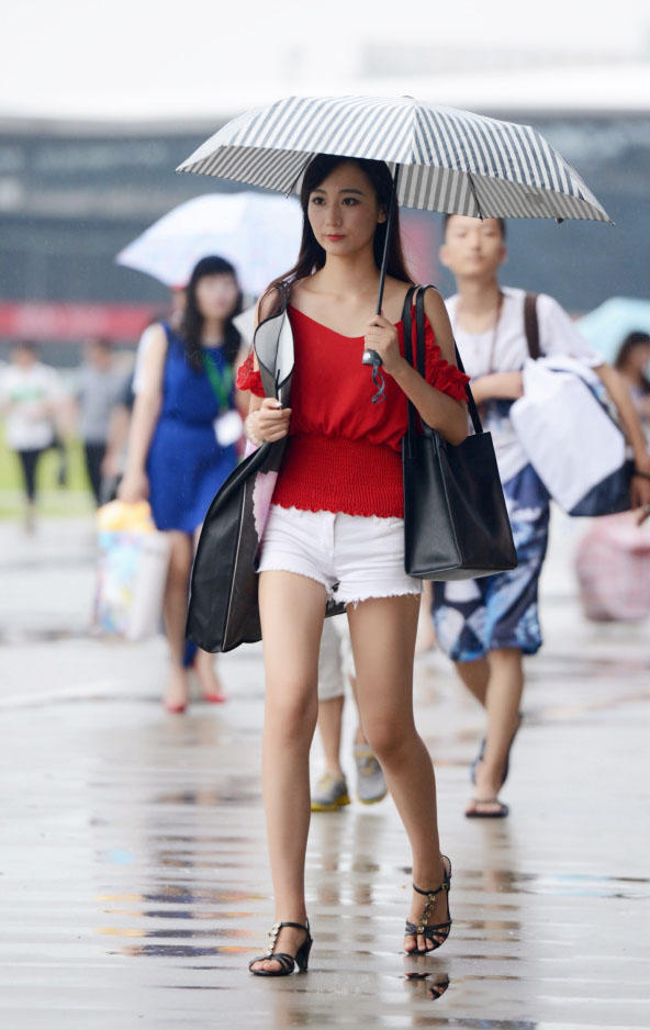 时尚小姐姐雨天上街，小热裤勾勒出修长美腿，伞下的她显得更加诱