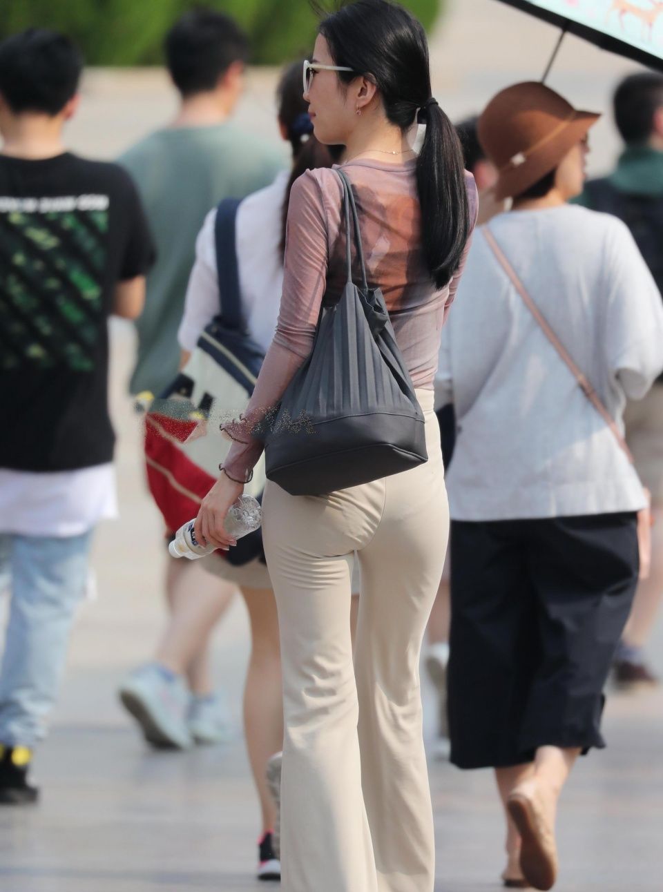 街拍美女:小姐姐白色紧身裤裹出迷人身型，一手举着扇子很怕太阳