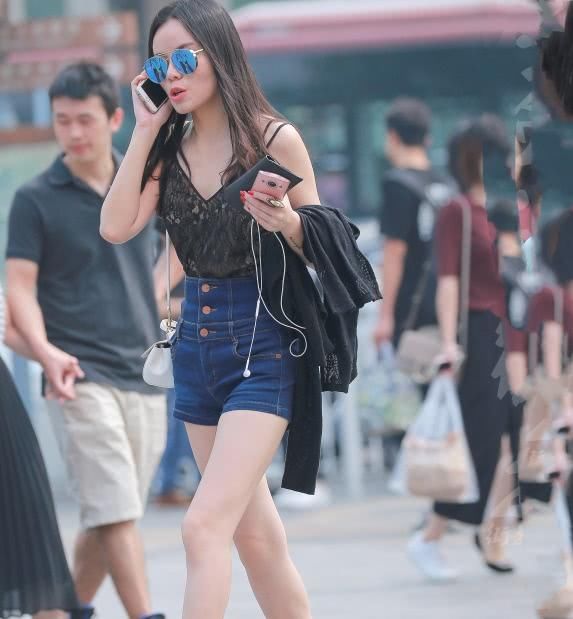 墨镜姐姐紧身牛仔短裤穿出修长大美腿，打电话的表情有些羞涩
