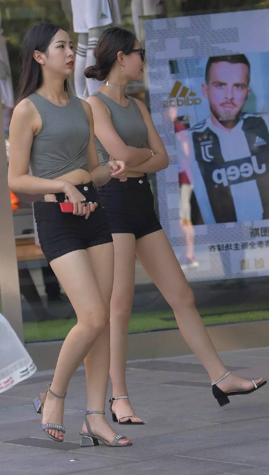 靓丽姐妹花同款紧身装街头比美，黑色超短裤秀出白皙大长腿