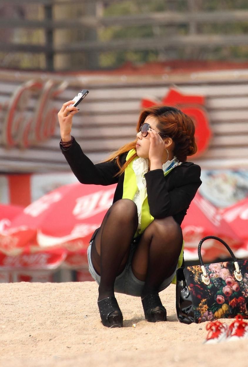 街拍:阳光沙滩上蹲姿曼妙的美女，细腻的黑丝更加灵动