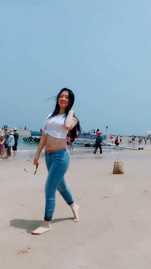 牛仔裤妹子穿高跟鞋太久了，索性光脚与沙滩来一次亲密接触