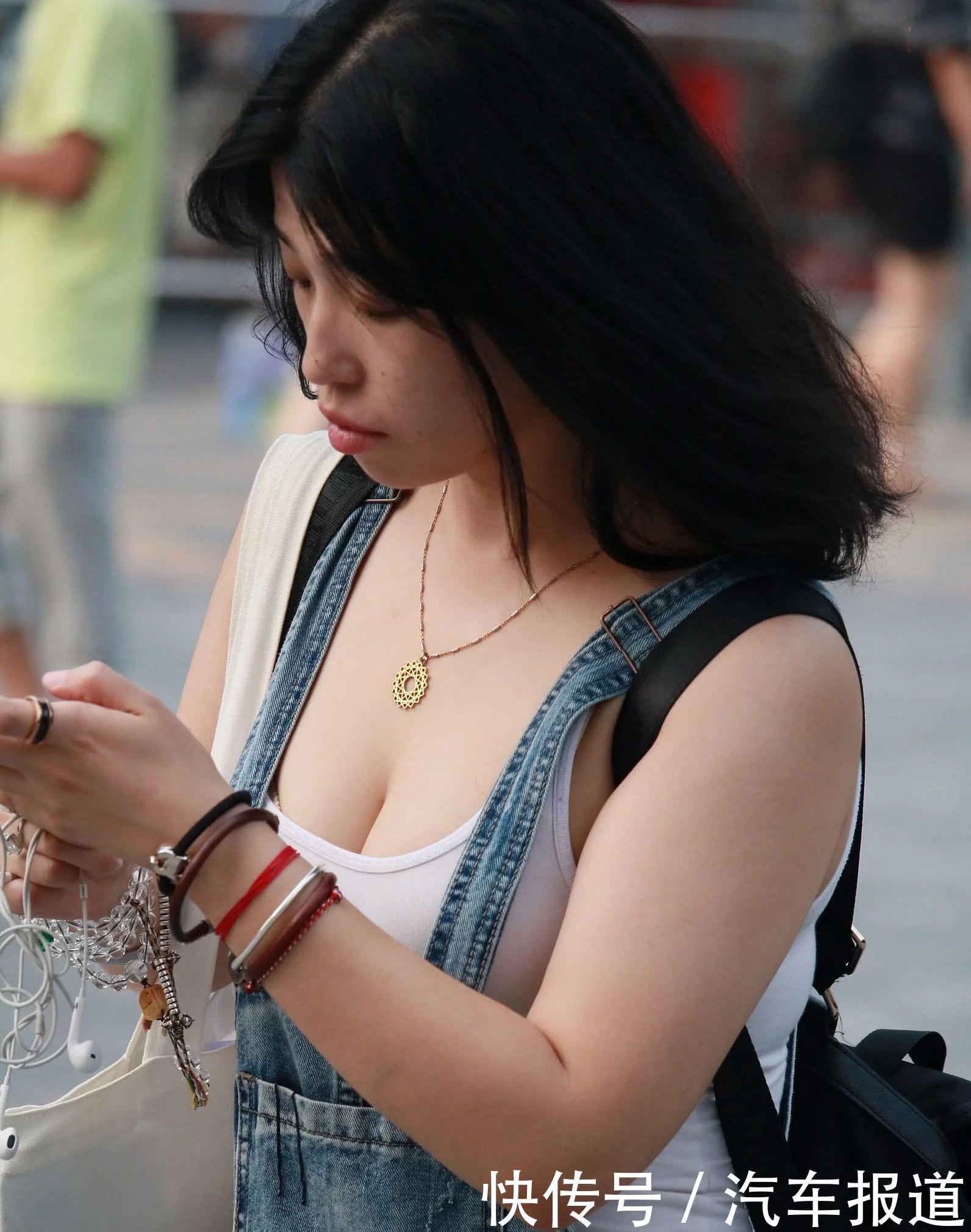 只顾低头玩手机的妙龄少妇，背心下包裹着傲人的玲珑身材，走在大