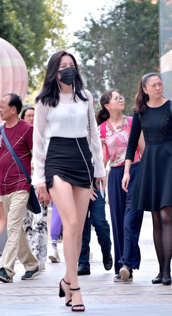 成熟小姐姐穿黑色超短裙勾勒出饱满圆润的臀线，一双美腿太撩人了