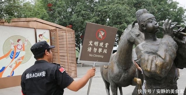 游客攀爬景区雕塑拍照，保安喊话劝告无效，沉默地递上一牌子