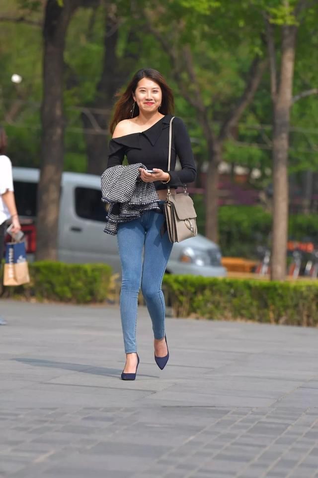 秀肩长袖上衣搭配紧身牛仔裤，自信笑容甜美街头