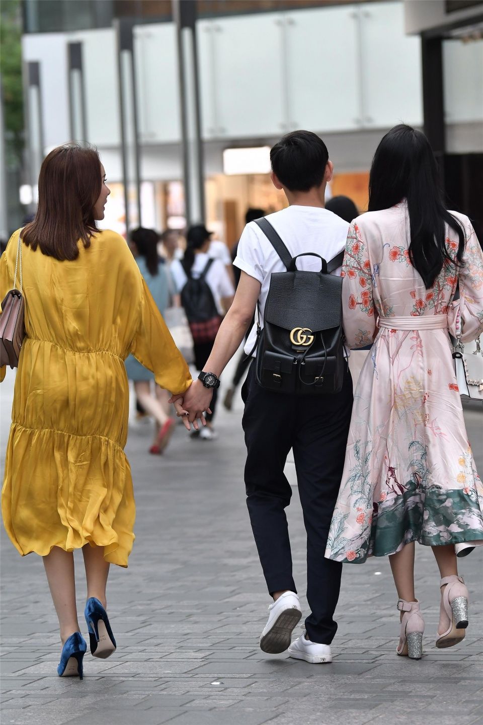 小伙子带着两位时尚长裙的姑娘，哪一位是他的女友呢?