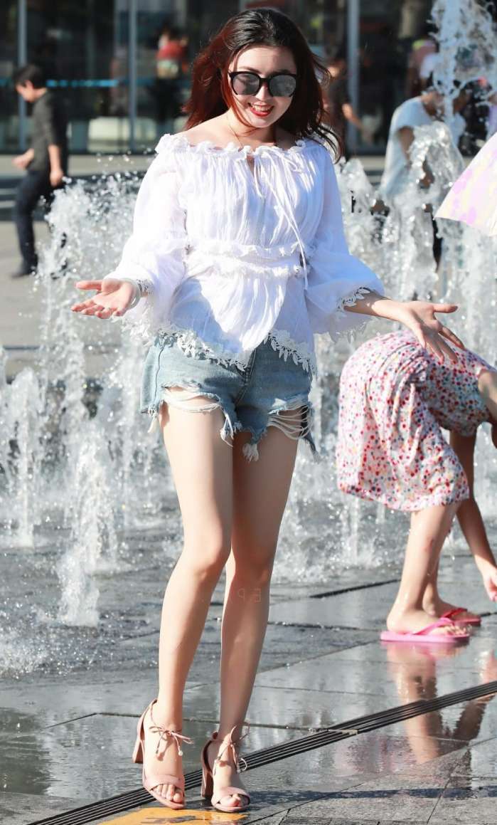 街拍：婴儿肥小姐姐牛仔短裤大秀时尚美腿，看到喷泉立马就玩嗨了