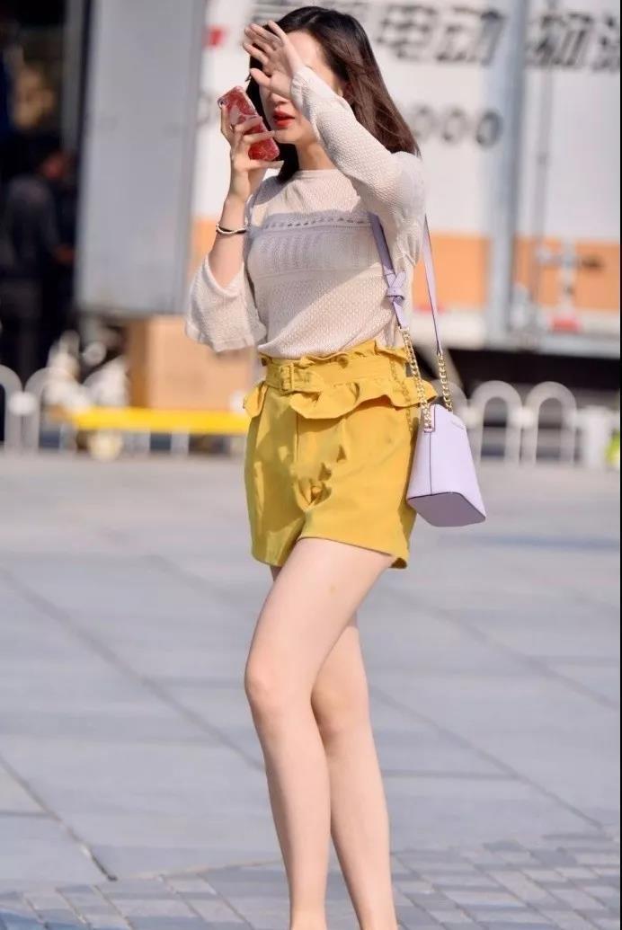 街拍：肤色白皙穿黄色短裤的年轻靓丽性感美女