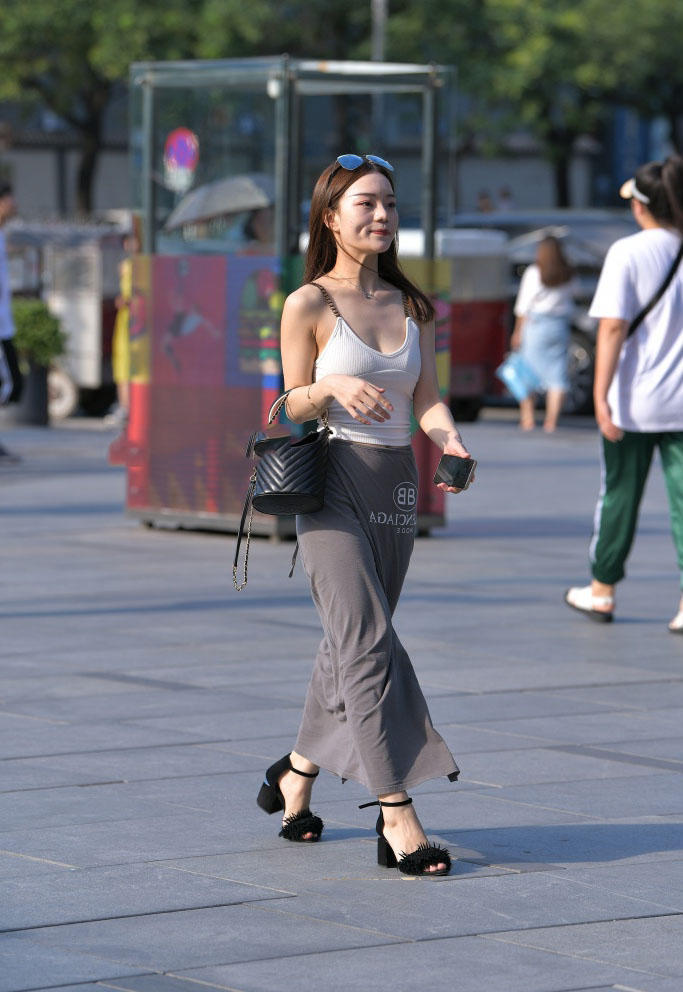 轻熟小女人穿高开叉连衣裙秀出一双修长纤细的美腿，风吹起裙角很