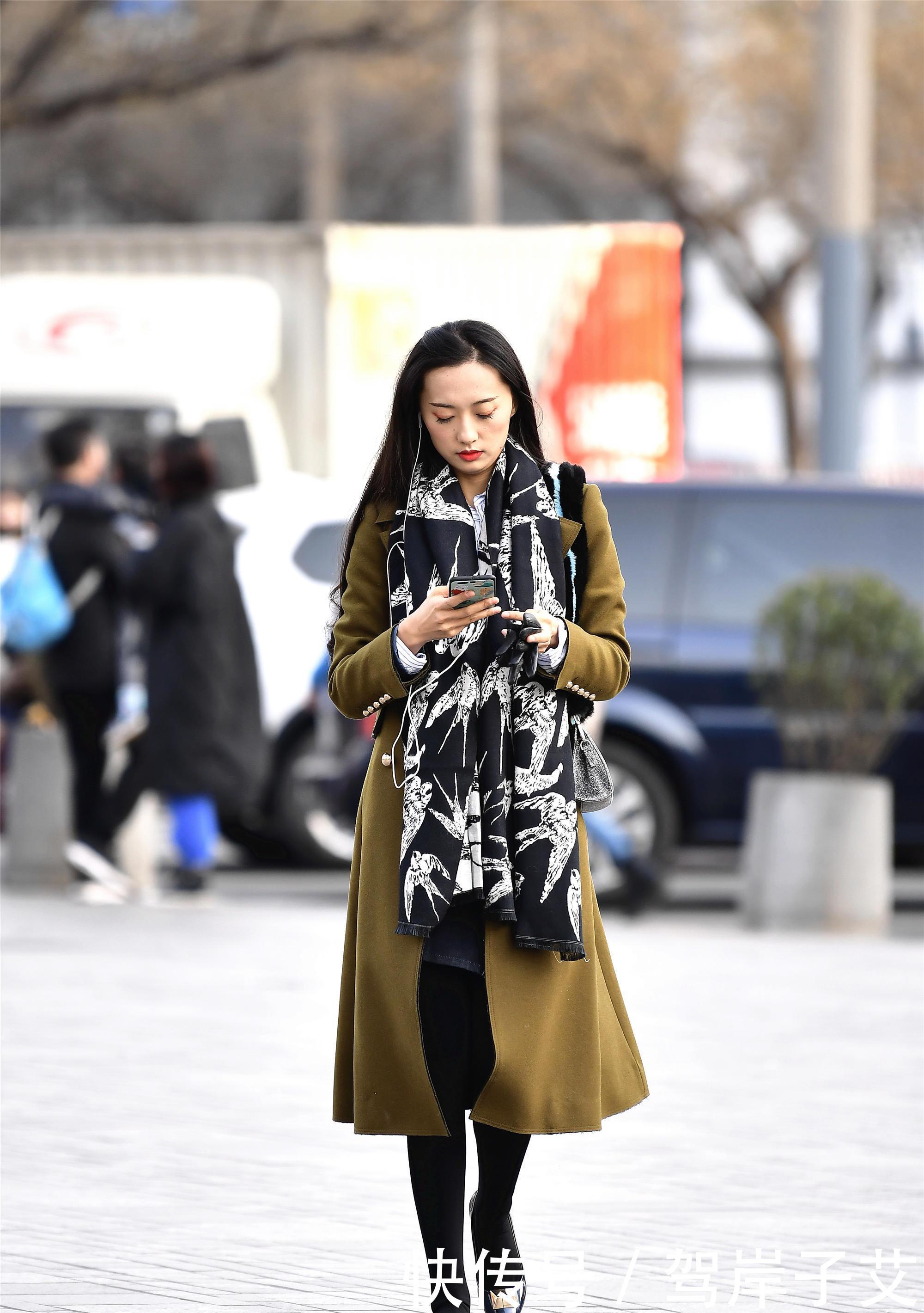 美女■街拍:美女搭配黄绿色的风衣,一条黑色打底裤,身材高挑美丽时尚