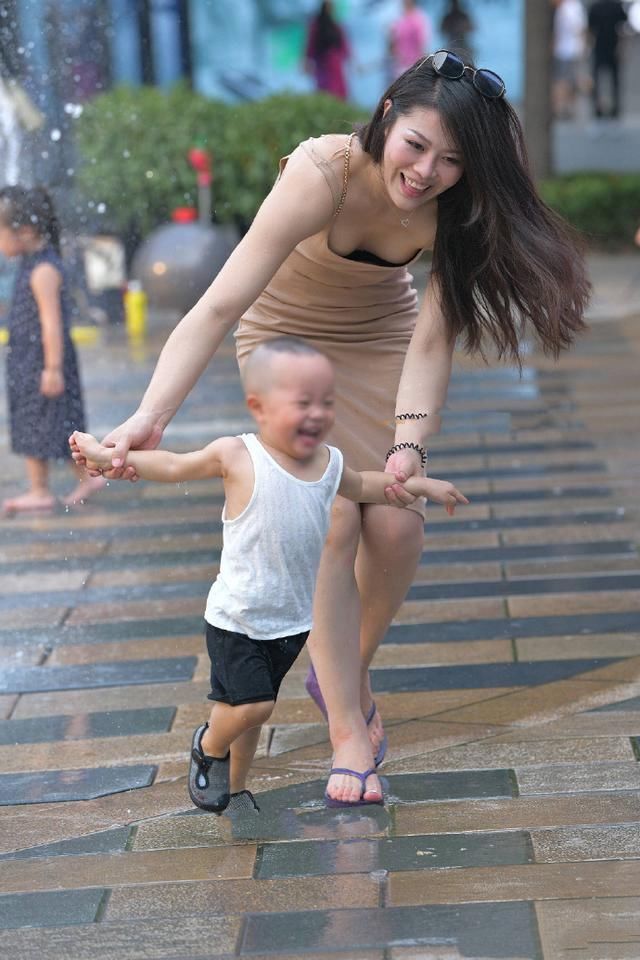 时尚辣妈,身穿肉色吊带连衣裙,俯身牵着孩子的手画面感好美!