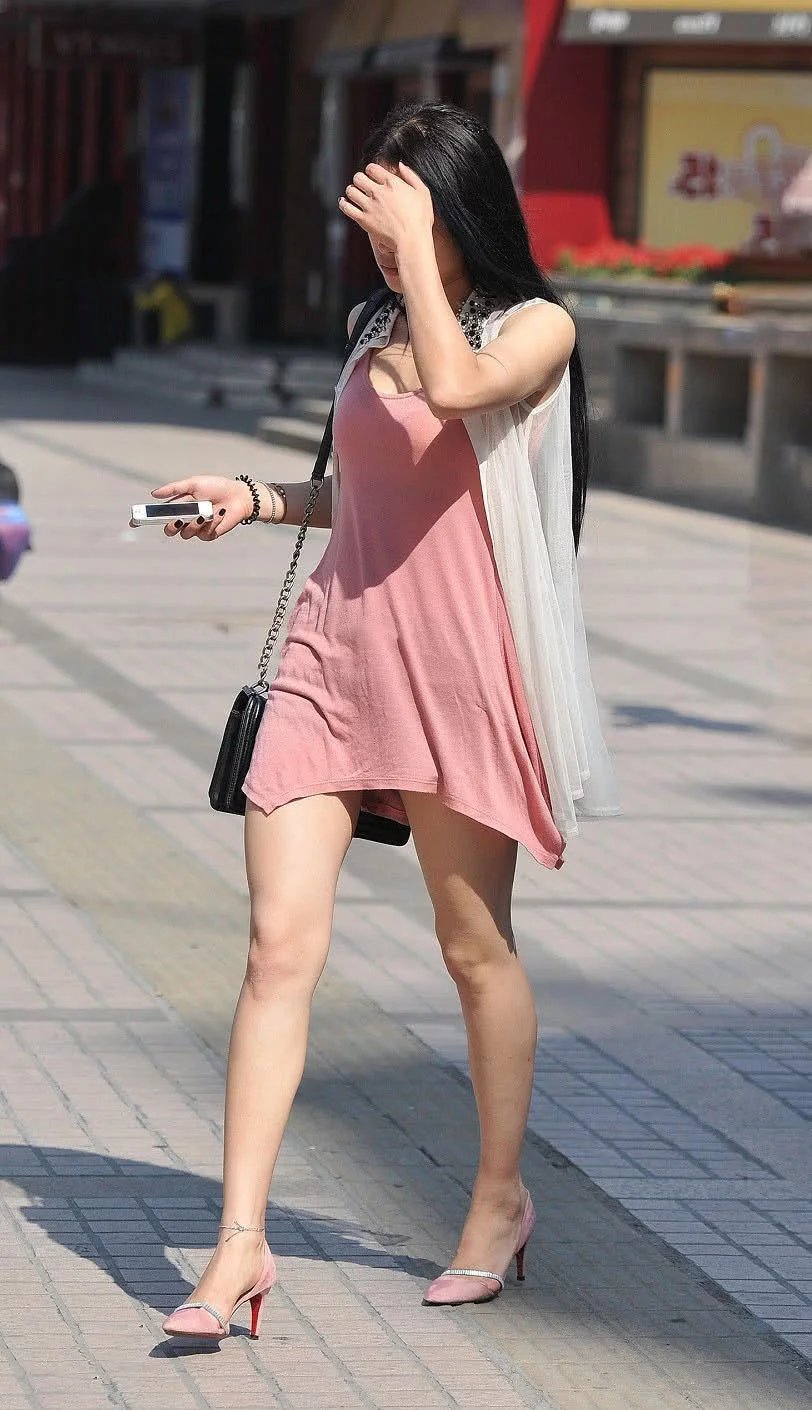 优雅的小姐姐粉红吊带裙勾勒丰满上围，拿手遮阳的样子很有小女人