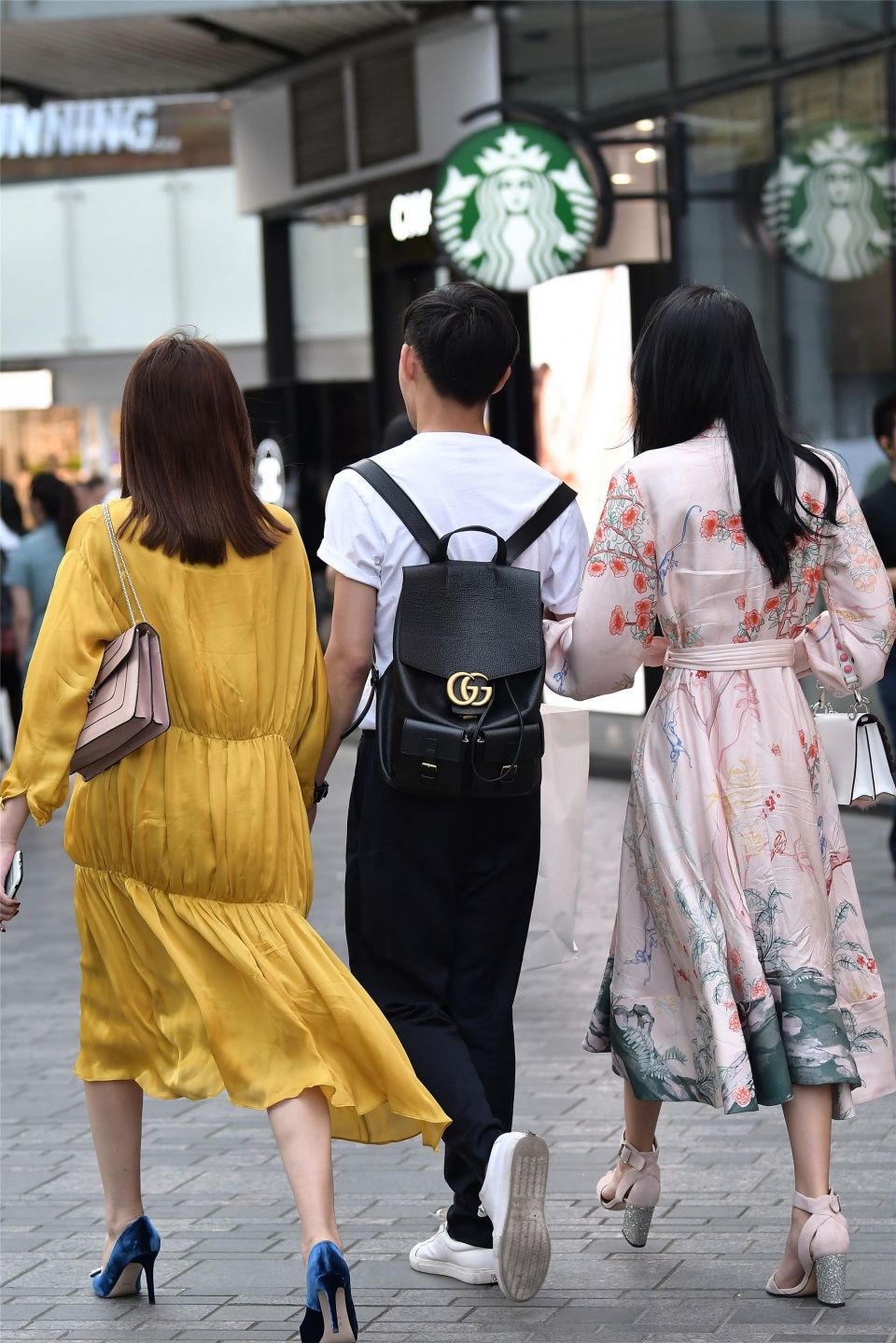 小伙子带着两位时尚长裙的姑娘，哪一位是他的女友呢?