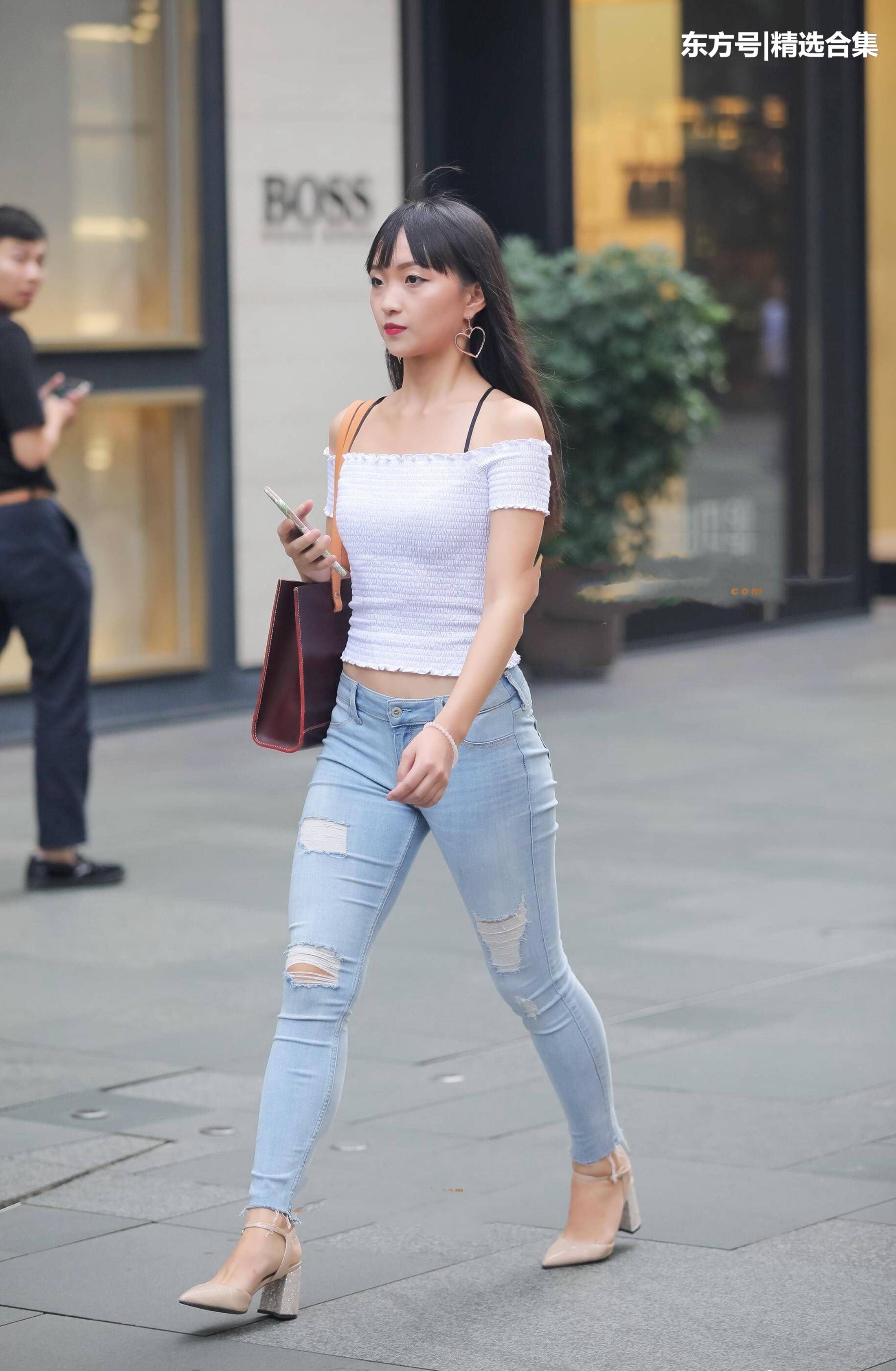 街拍美女:破洞紧身牛仔裤搭配白色漏肩针织衫，很素雅的小姐姐