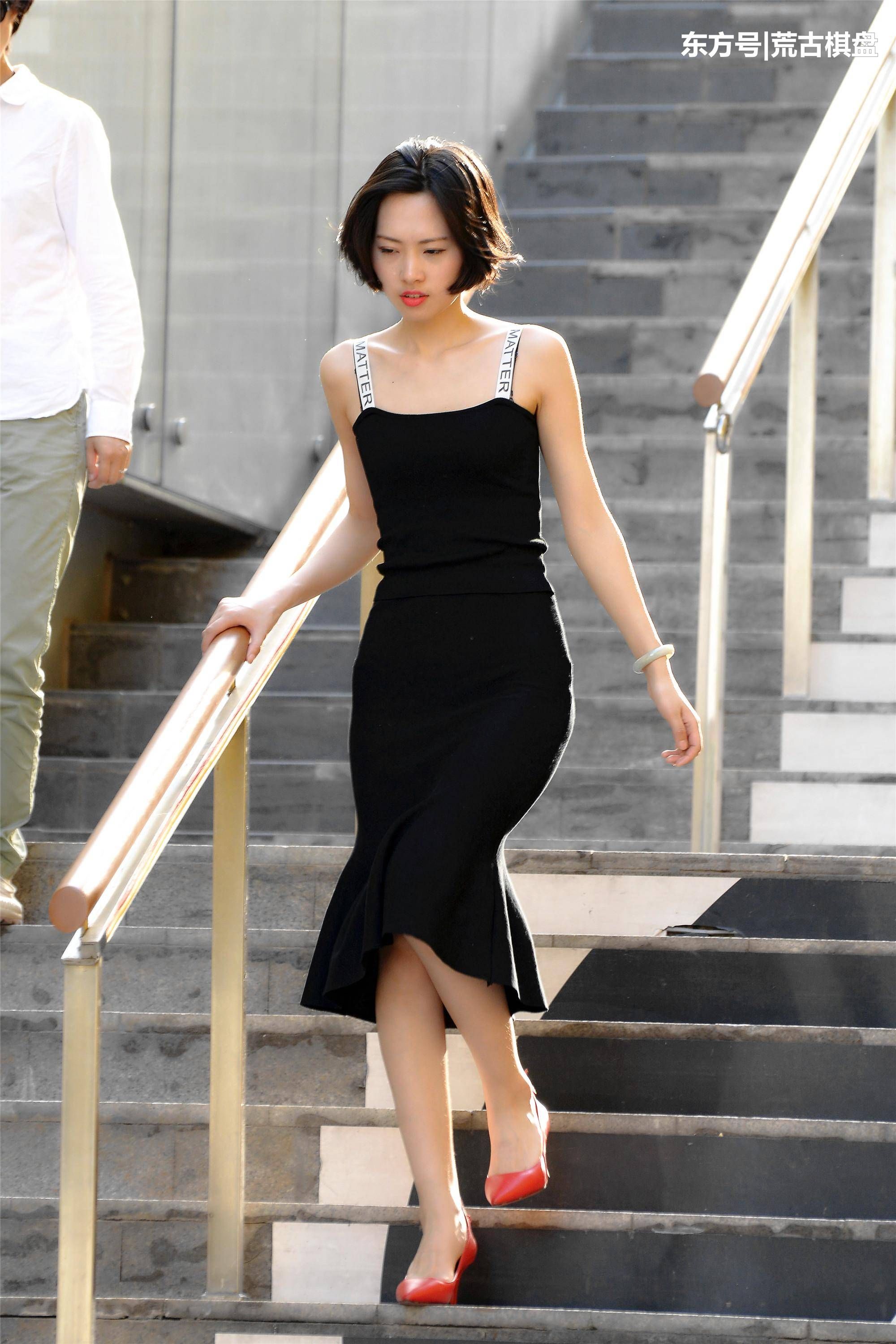 黑色吊带长裙姑娘穿着尖头细高跟在台阶上走上走下，忙碌着什么?