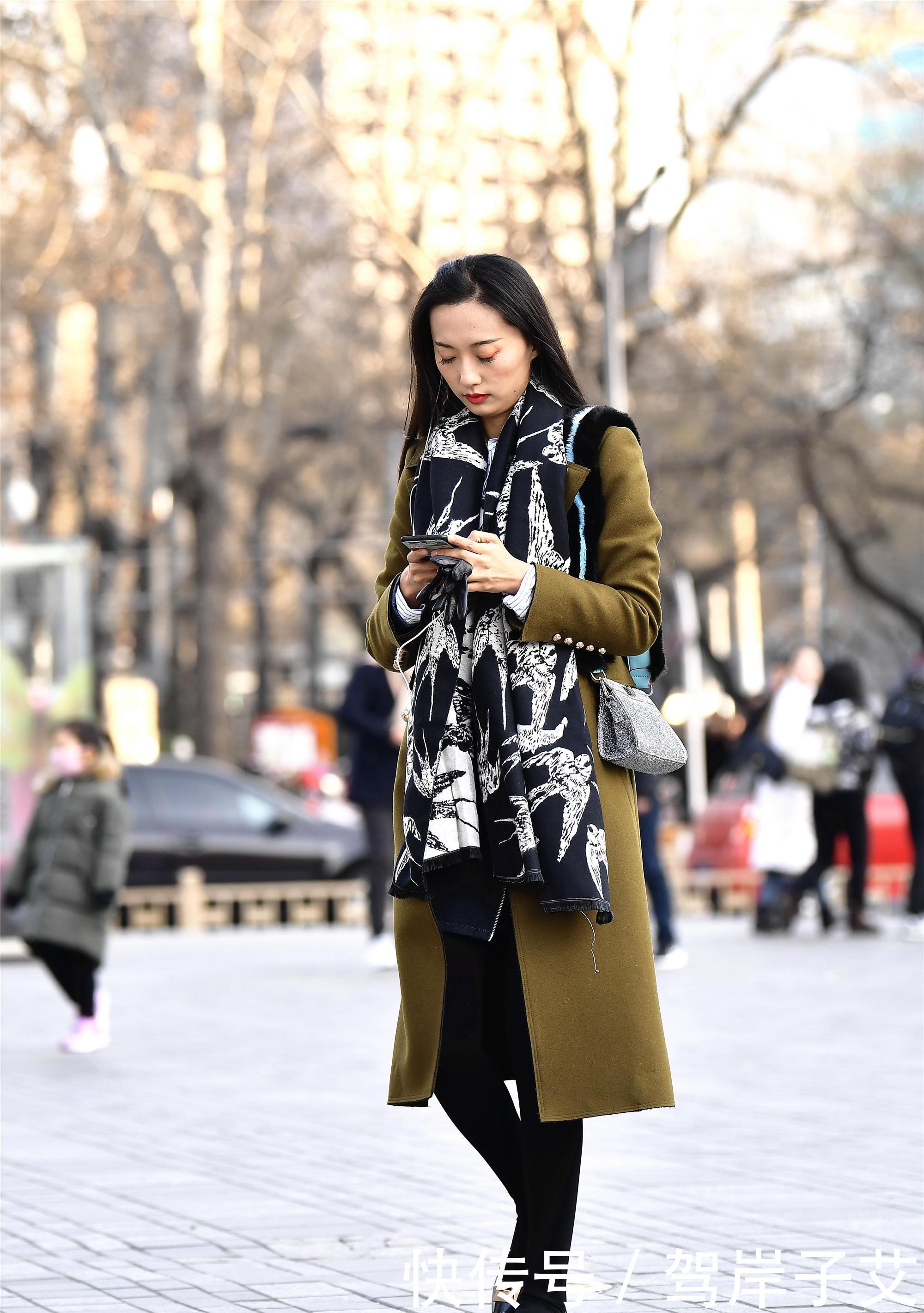 美女■街拍:美女搭配黄绿色的风衣,一条黑色打底裤,身材高挑美丽时尚