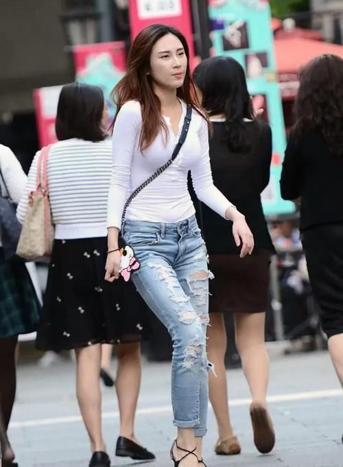  轻松■街拍：小姐姐的牛仔裤穿着轻松时髦，破洞设计增加了随心潇洒风格