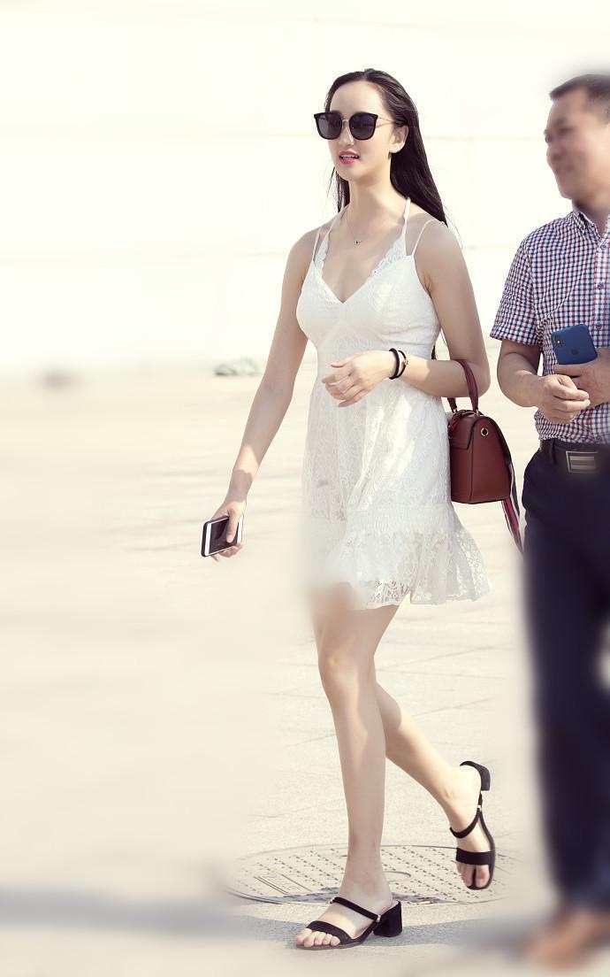 街拍：气质小姐姐紧身牛仔裤搭粉色吊带上衣凸显好身材，打扮迷人