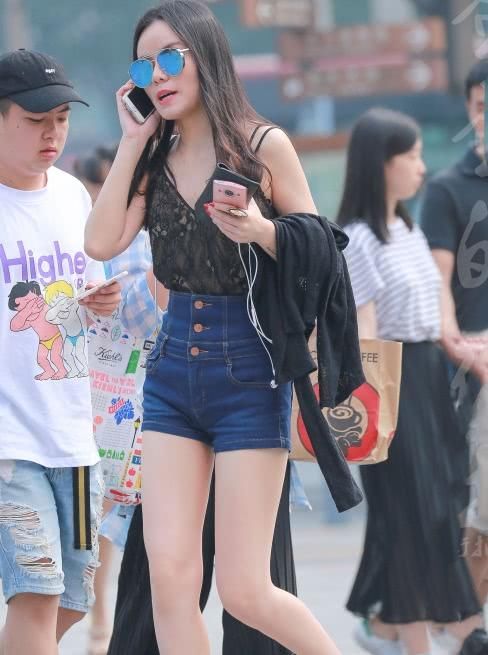 墨镜姐姐紧身牛仔短裤穿出修长大美腿，打电话的表情有些羞涩