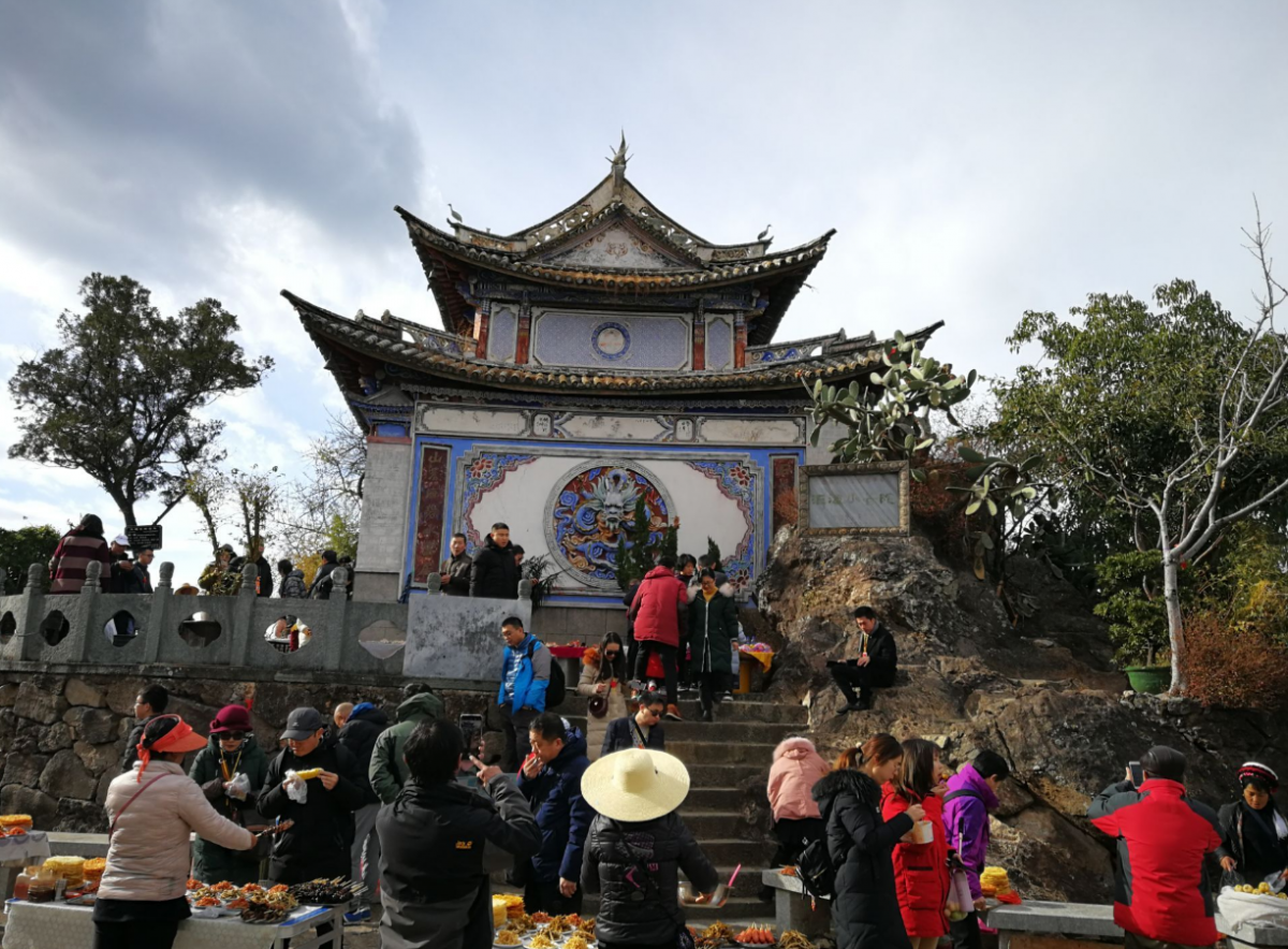 云南一个寺庙,被小吃摊包围,墙都被烧烤的油烟熏黑了!