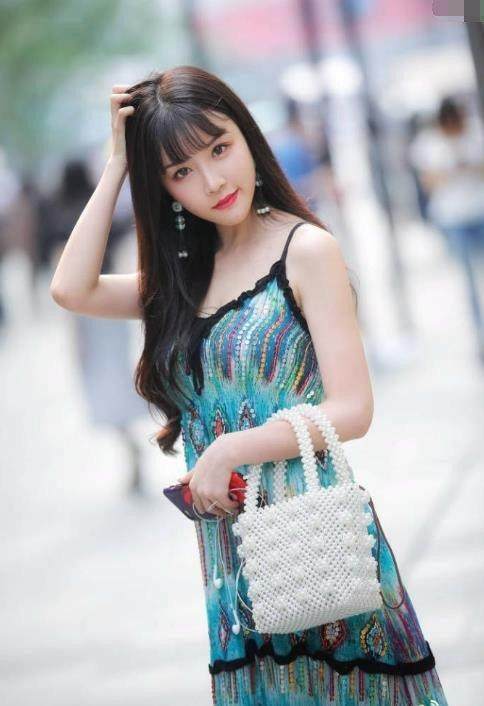 街拍：婴儿肥小姐姐孔雀翎吊带裙显出完美身姿，令人难以移开目光