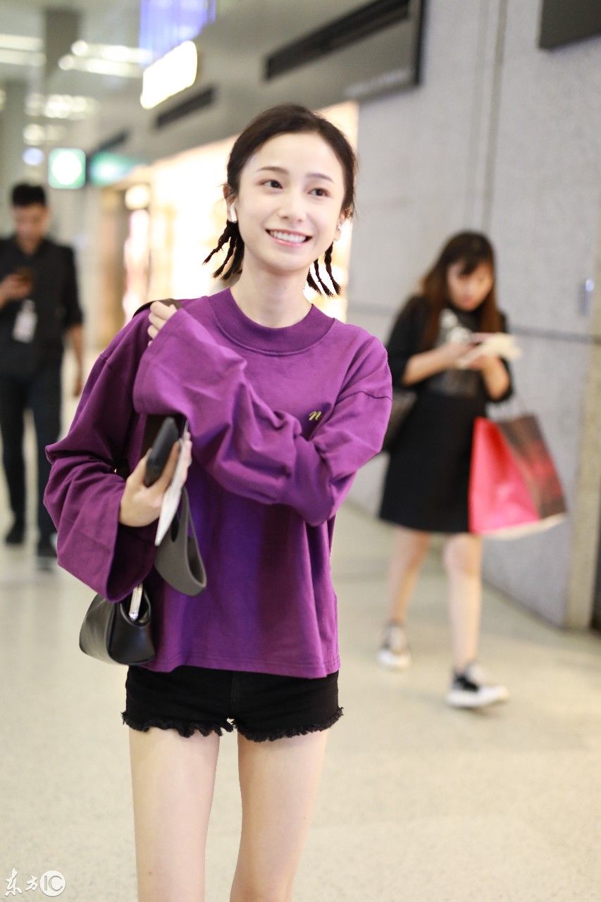姜梓新穿紫色卫衣搭配黑短裤现身机场，皮肤白皙面带微笑大秀美腿