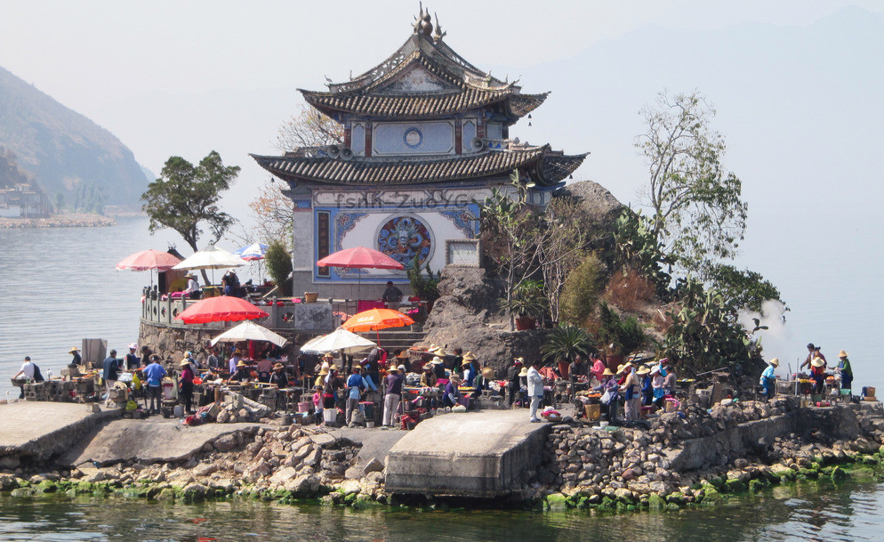 云南一个寺庙,被小吃摊包围,墙都被烧烤的油烟熏黑了!