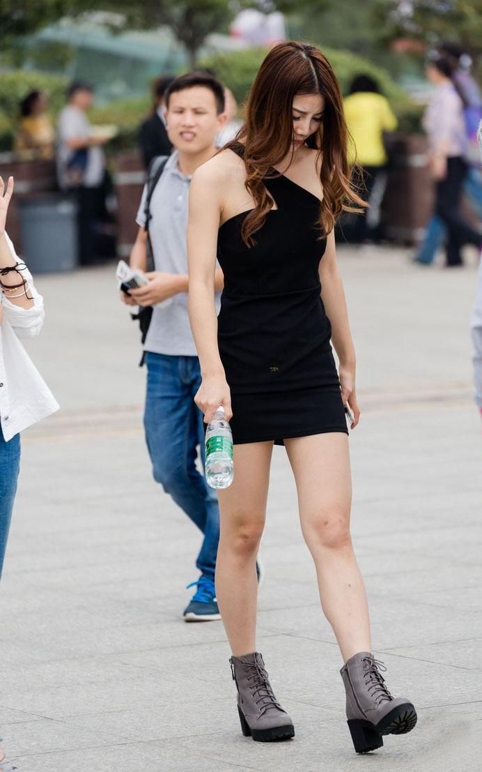 街拍:紧身短裙露肩装的美女很是吸人眼球，后面男子看得两眼发愣