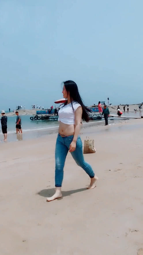 牛仔裤妹子穿高跟鞋太久了，索性光脚与沙滩来一次亲密接触