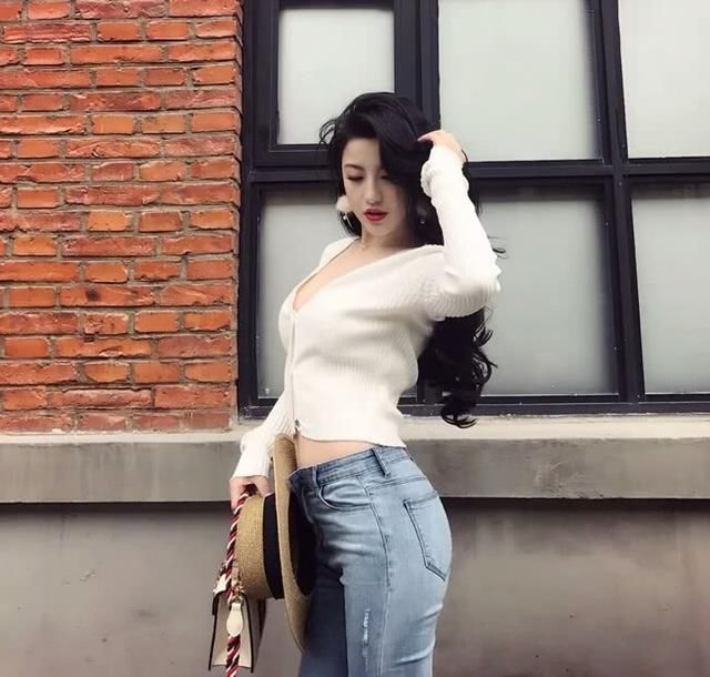 牛仔裤+高跟鞋起到了提臀效果，美女长发飘飘，温暖可人