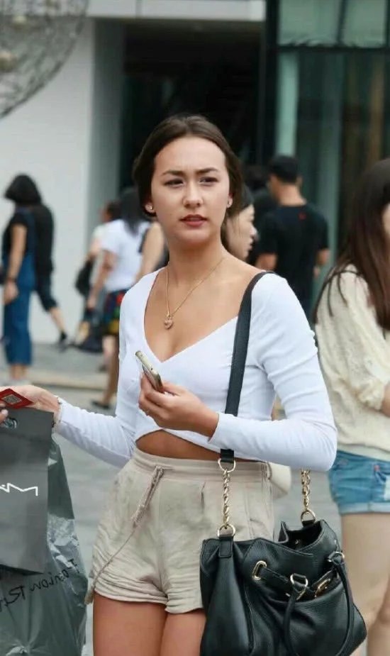 长相甜美的小姐姐，身穿露脐装下身米白色短裤大秀傲人身材