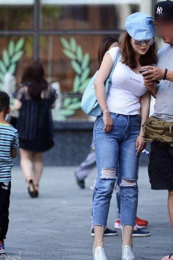 街拍:美女穿破洞牛仔裤,优雅的姿态,充满自信的笑容