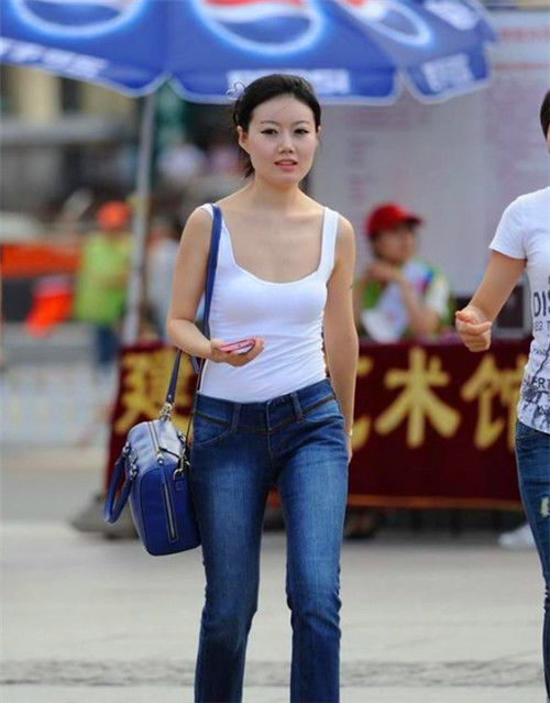 小美女:街拍:小美女身穿黑色套装,手里拿着包包,笑容甜美