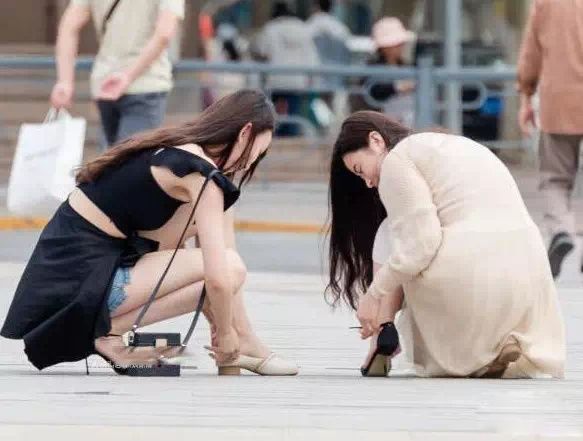 街拍丨两位美女街上互换鞋子，姿态真心美腻!