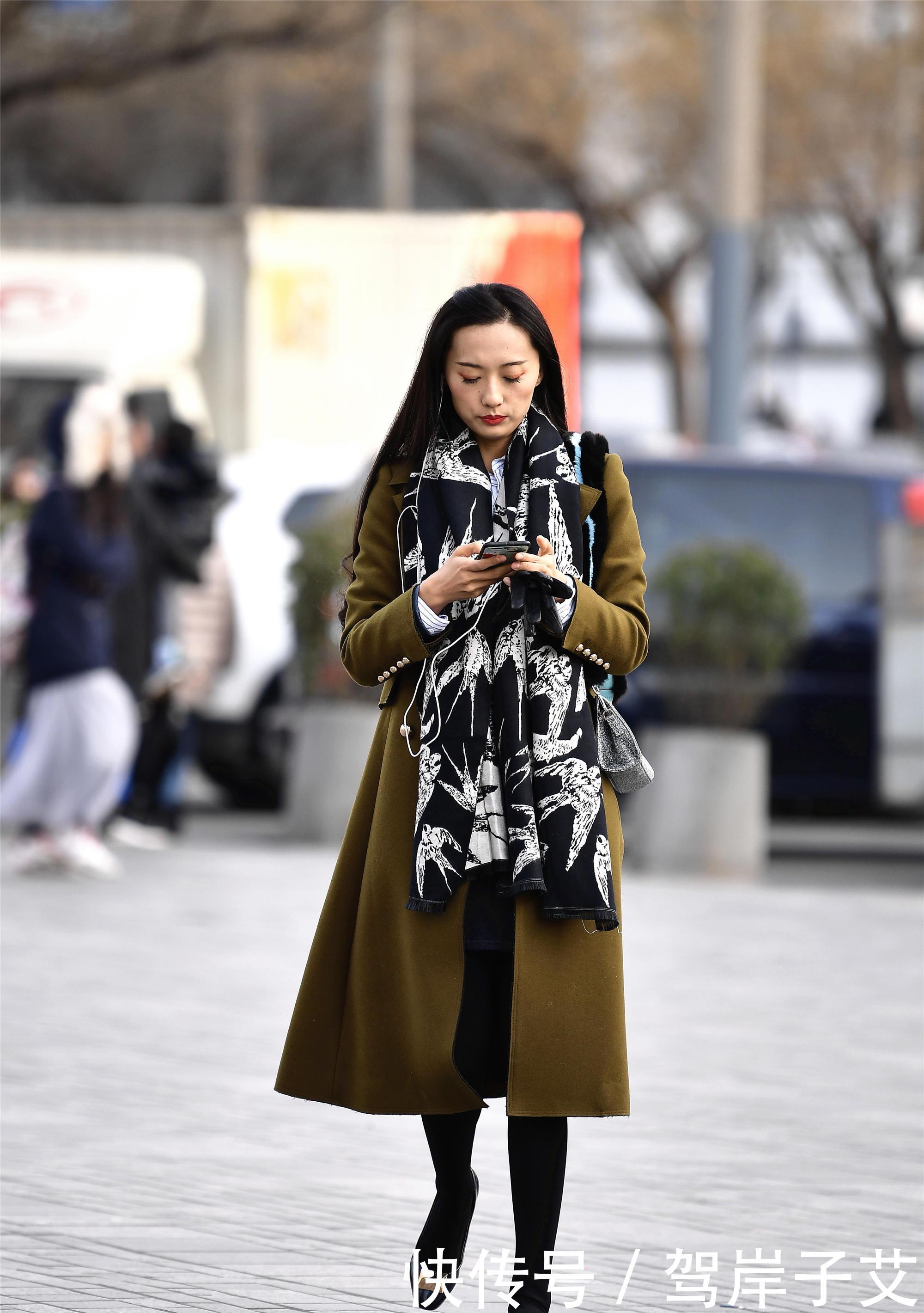 美女■街拍:美女搭配黄绿色的风衣,一条黑色打底裤,身材高挑美丽时尚