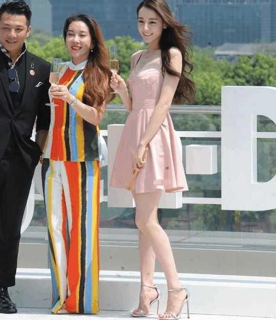 迪丽热巴淡妆出席活动，小粉裙配细高跟，风吹乱发型显“凌乱美”