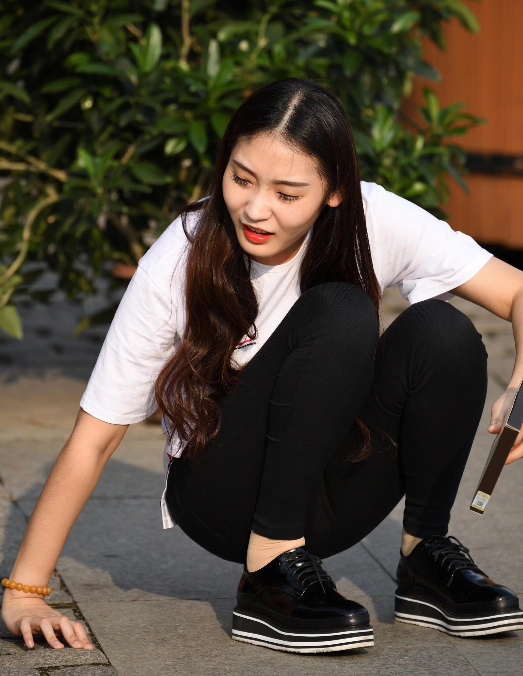 气质小姐姐盘腿坐在路边，紧身裤太紧绷，刚一起身差点儿没摔倒