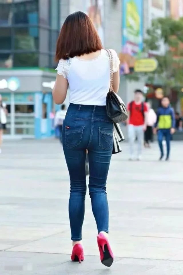 气质小姐姐白色T恤搭配牛仔裤,紧绷感十足,边走边玩手机很洋气